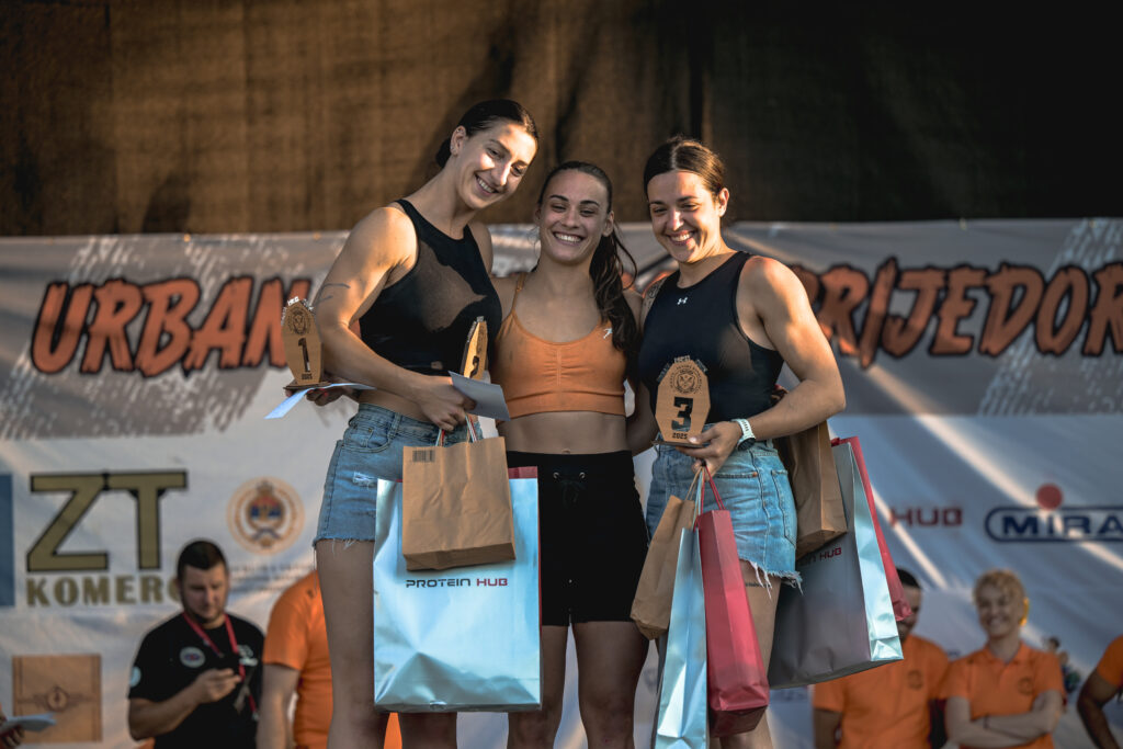 Pobjednice OCR trke Urban Rush stoje na pobjedničkom postolju s medaljama i osmijehom, slaveći uspjeh i sportski duh u Prijedoru.